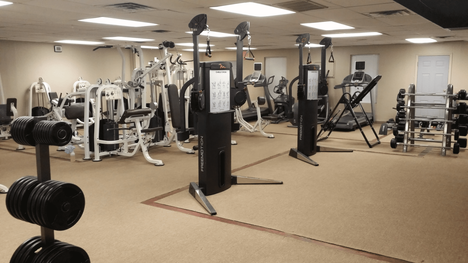 A gym with many machines and a few people
