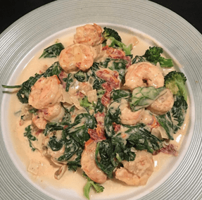 A plate of shrimp and spinach with cheese sauce.